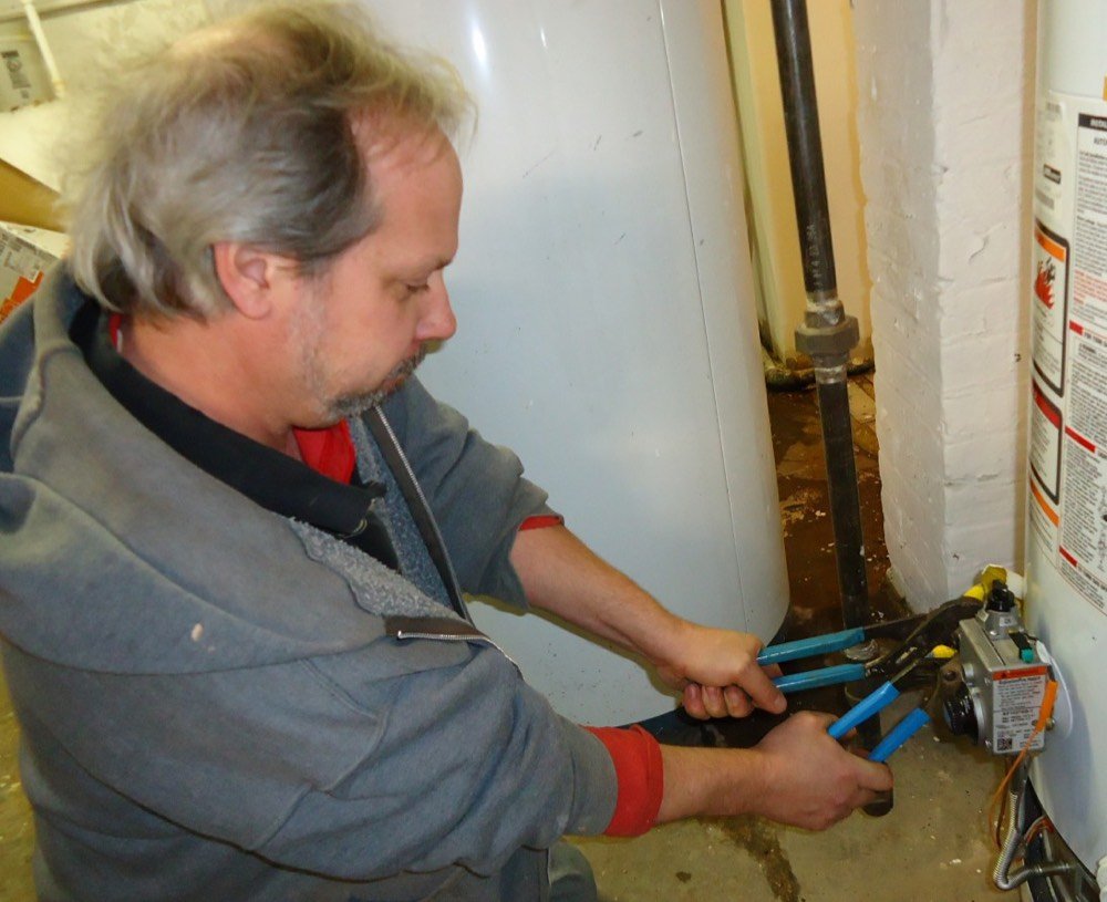 Plumber tightening a pipe fitting with wrenches